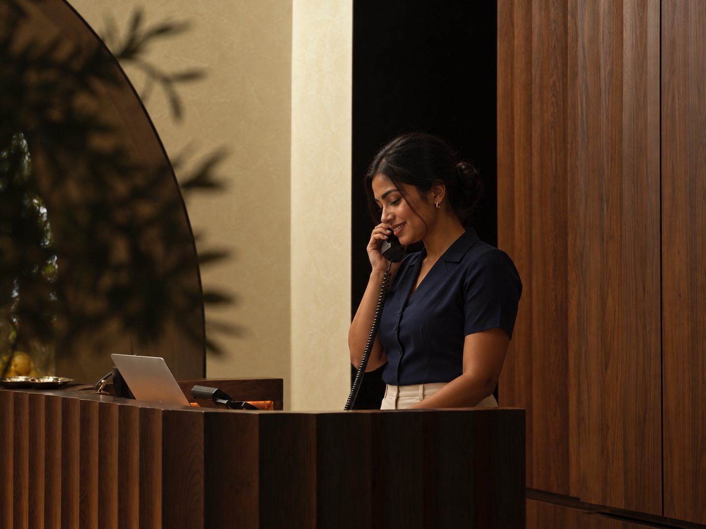 A smiling concierge answering a guest's call at a reception desk