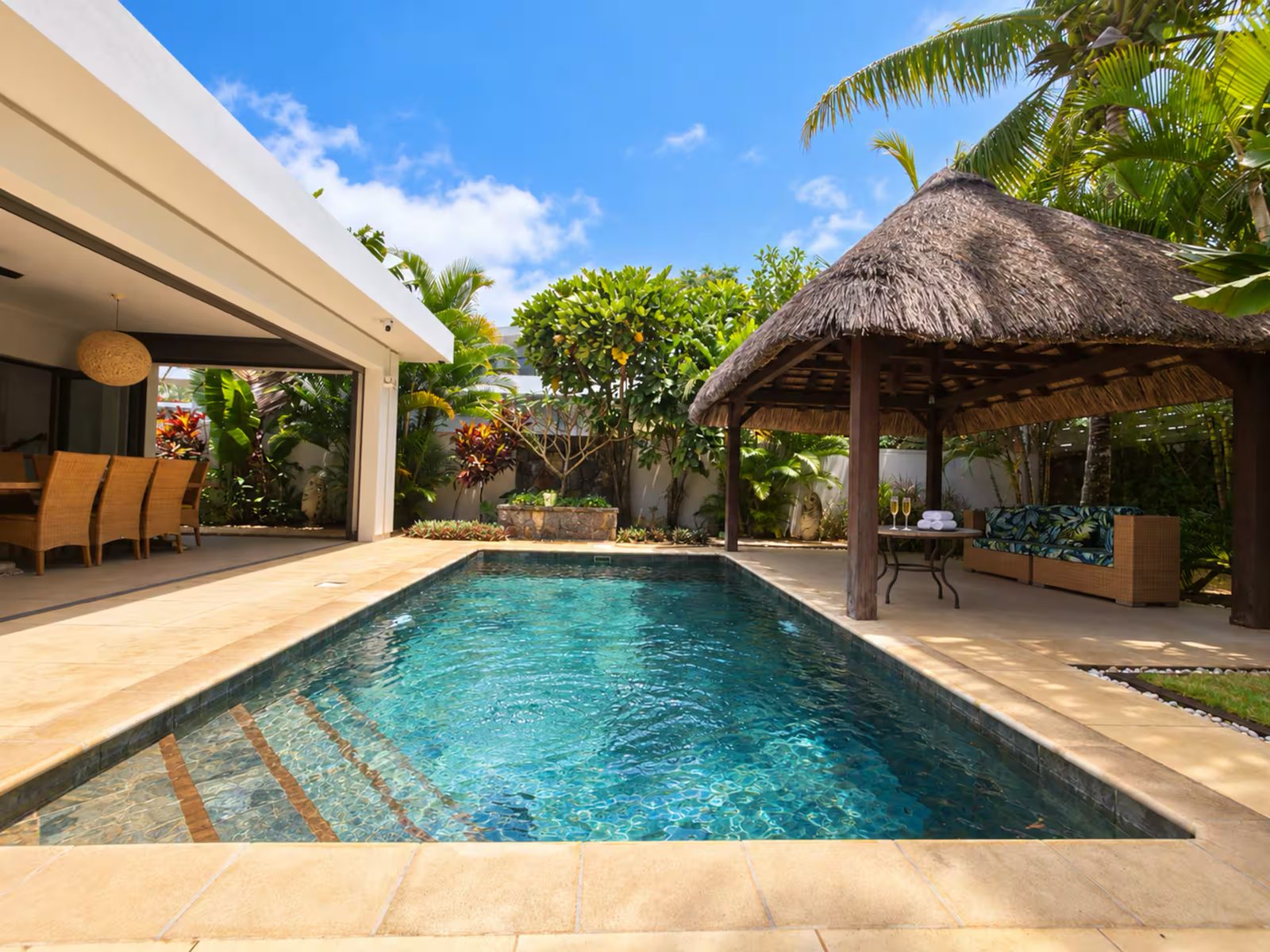 A private villa pool beside a thatched gazebo and tropical garden in Mauritius